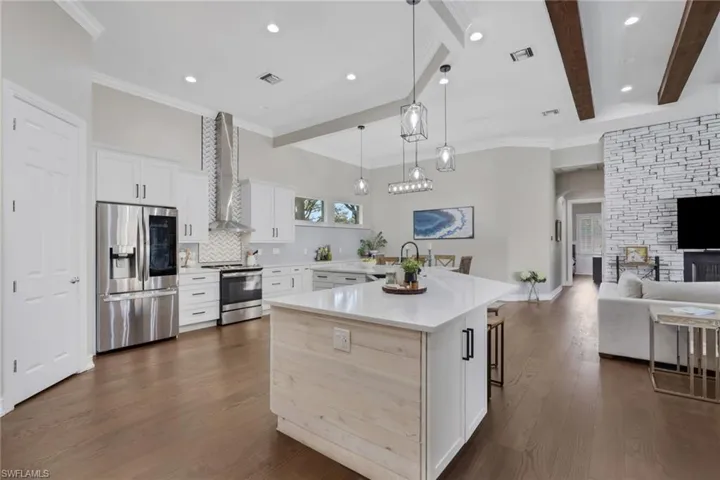 Kitchen with white cabinetry, stainless steel appliances, a kitchen breakfast bar, pendant lighting, and open floor plan