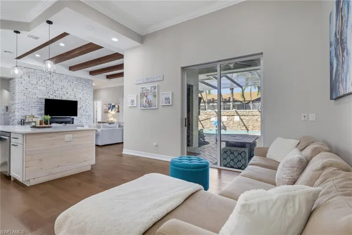Living room with beam ceiling, light wood finished floors, crown molding, and recessed lighting