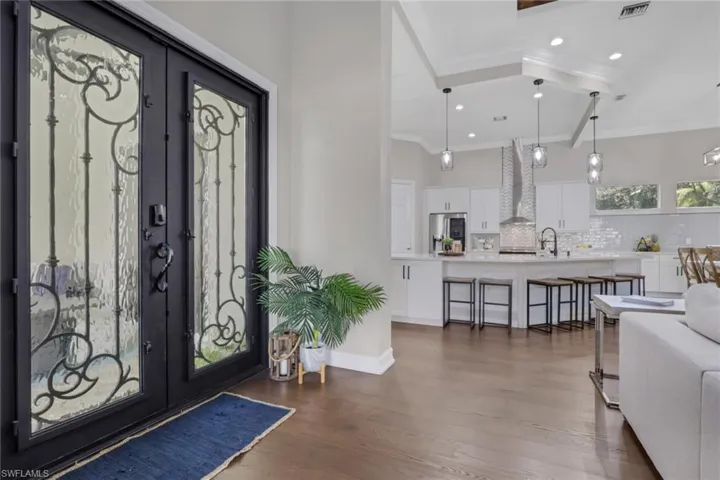 Foyer with dark wood-type flooring, french doors, crown molding, and recessed lighting