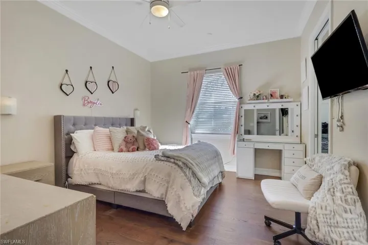Bedroom with crown molding, dark wood-style floors, and ceiling fan