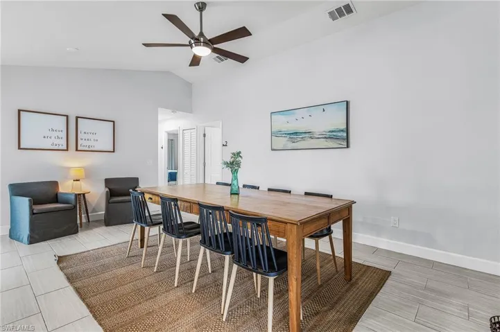 Vaulted ceiling dining area featuring light-toned tile flooring and a ceiling fan with integrated lighting