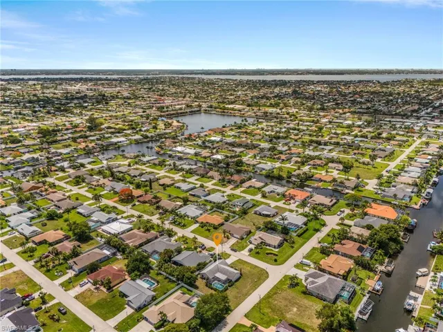 Expansive aerial capture showcasing a residential area with a prominent canal system and multiple properties featuring private boat docks