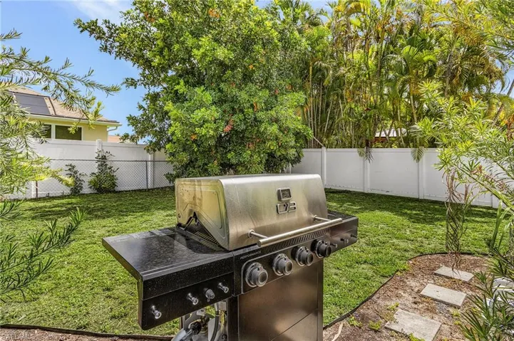Expansive backyard featuring a lush lawn, privacy fencing, mature trees, and landscaping with stepping stones
