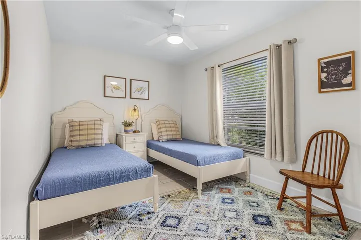Bedroom featuring a ceiling fan with integrated lighting, wood-finish flooring, a window with horizontal blinds, and neutral wall paint