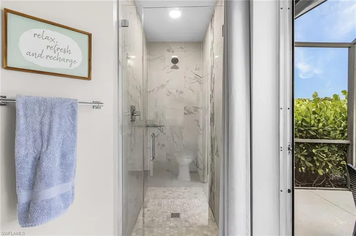 Glass-enclosed shower featuring full-height marble-look tile walls, a rain showerhead, a built-in bench with mosaic tile, and a handheld shower fixture