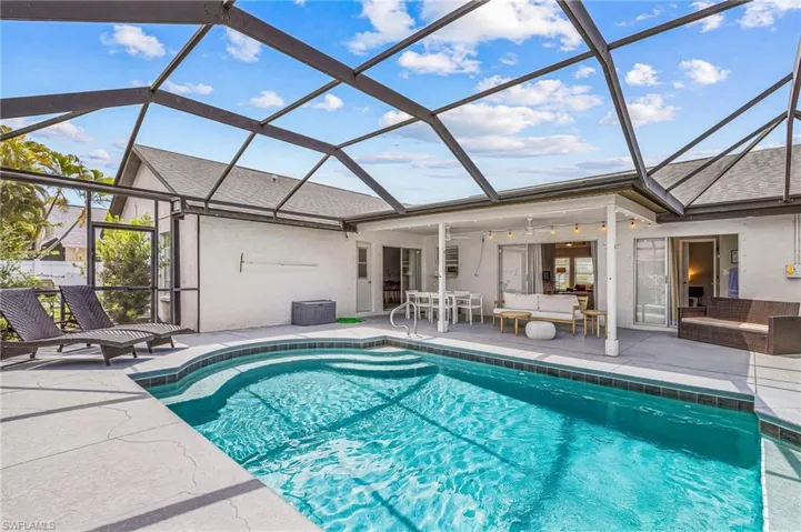 Screened outdoor living area featuring a rectangular pool with integrated steps, a covered patio, and multiple sliding glass door entries