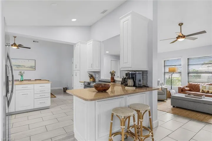 Modern kitchen featuring white cabinetry, light-toned countertops, a subway tile backsplash, stainless steel appliances, and tile flooring
