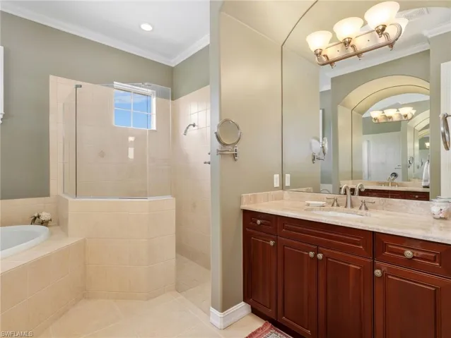 Primary En-Suite Bathroom with Crown Molding, Dual Vanities & Sinks, Cultured Marble Countertops, Separate Tub, & Walk-In Shower with Glass Enclosure