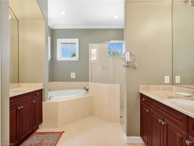 Primary En-Suite Bathroom with Crown Molding, Dual Vanities & Sinks, Cultured Marble Countertops, Separate Tub, & Walk-In Shower with Glass Enclosure