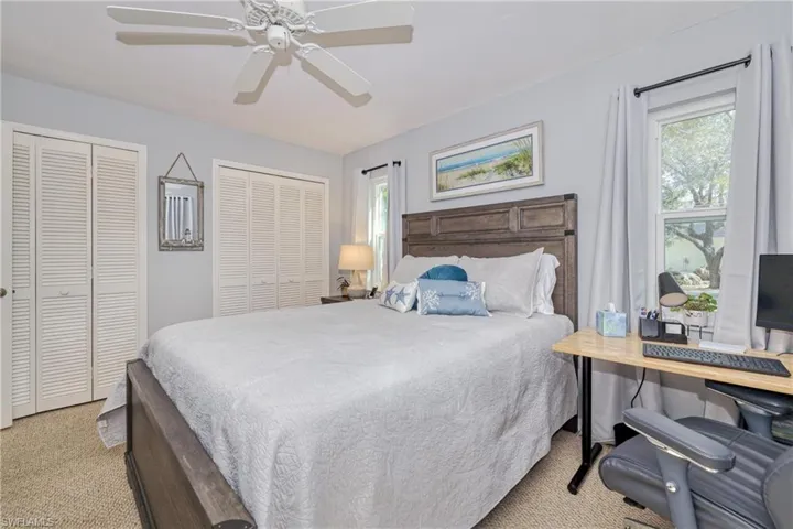 Carpeted bedroom with ceiling fan and two closets