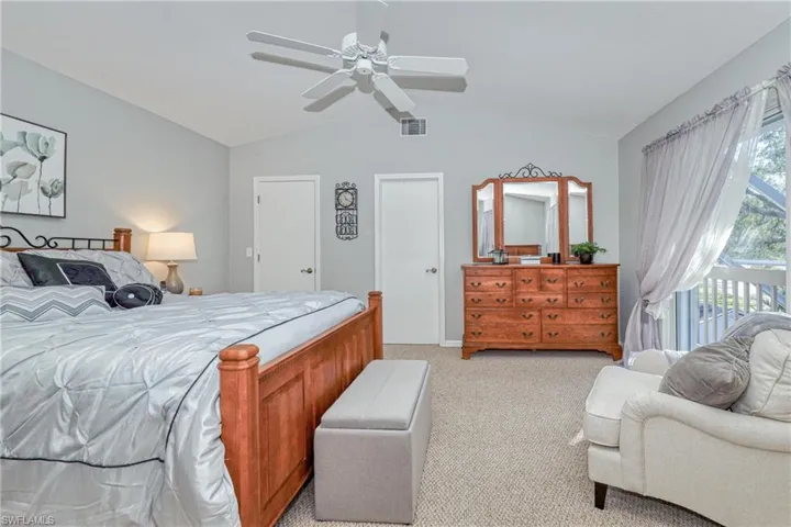 Bedroom with vaulted ceiling, light carpet, access to exterior, and ceiling fan