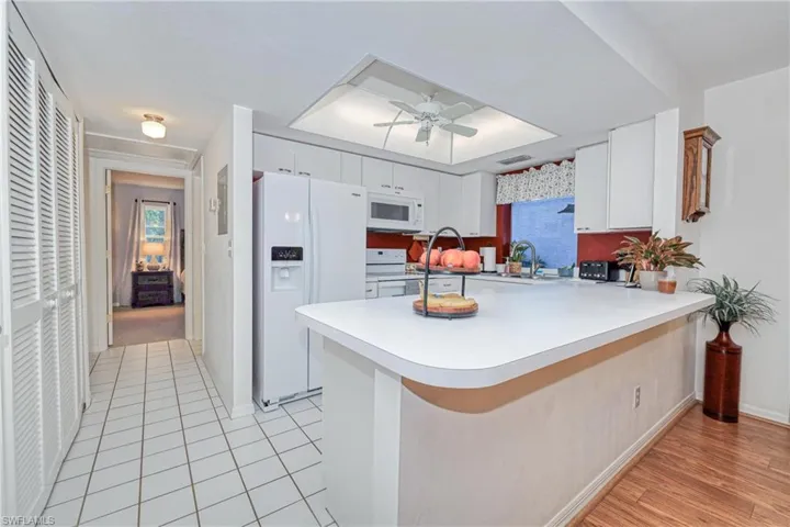 Kitchen with sink, white appliances, ceiling fan, white cabinetry, and kitchen peninsula