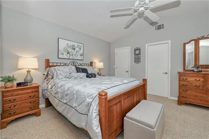 Bedroom with lofted ceiling, light colored carpet, and ceiling fan