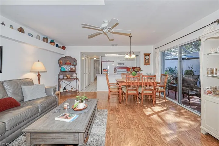 Living room with ceiling fan with notable chandelier and light hardwood / wood-style flooring