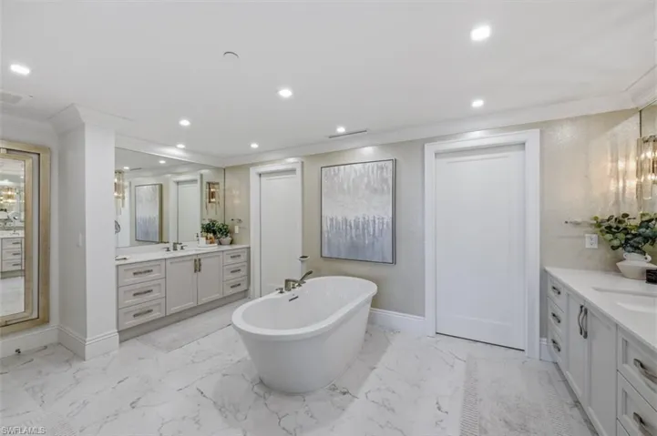 Freestanding soaking tub with a floor-mounted fixture, set against marble-look tile flooring