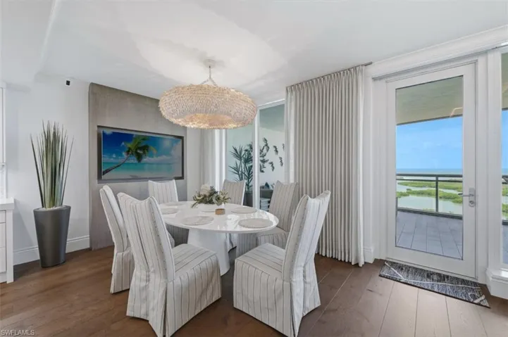 Dining area featuring rich wood-finish flooring, a contemporary oval dining table, and a woven pendant light fixture