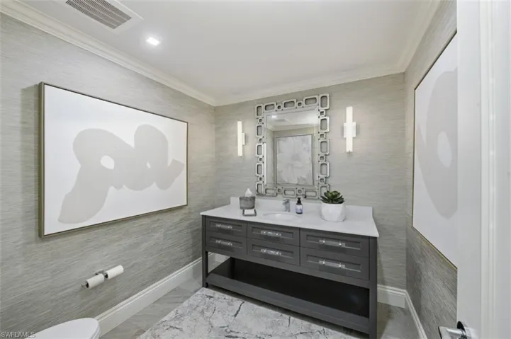 Contemporary vanity with a white countertop and undermount sink, accented by two wall sconces and a decorative mirror