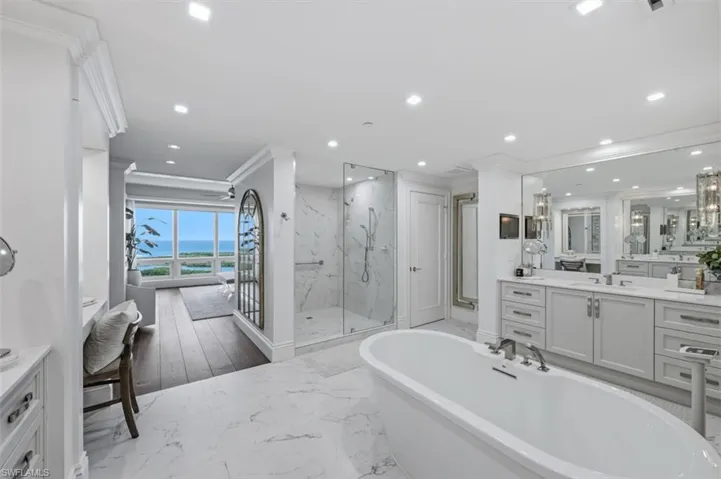 Freestanding soaking tub with a floor-to-ceiling window offering water scenery