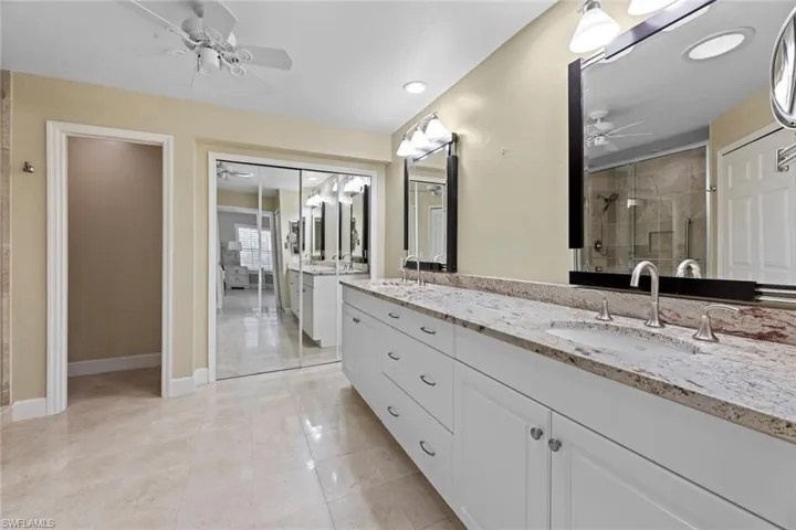 Bathroom with a shower with shower door, tile flooring, dual vanity, and ceiling fan