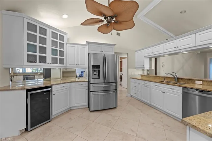 Kitchen with appliances with stainless steel finishes, white cabinetry, sink, and wine cooler