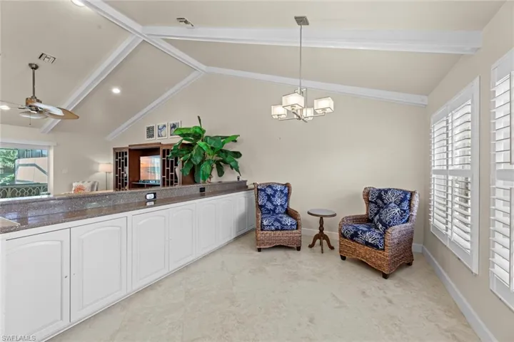 Living area with ceiling fan with notable chandelier, lofted ceiling with beams, and light tile floors