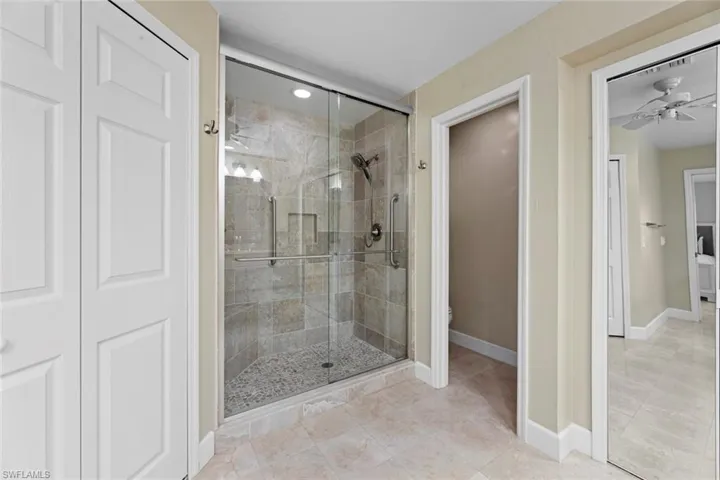 Bathroom with tile flooring, an enclosed shower, and ceiling fan