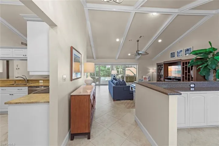 Kitchen with ceiling fan, stainless steel dishwasher, white cabinets, sink, and lofted ceiling with beams