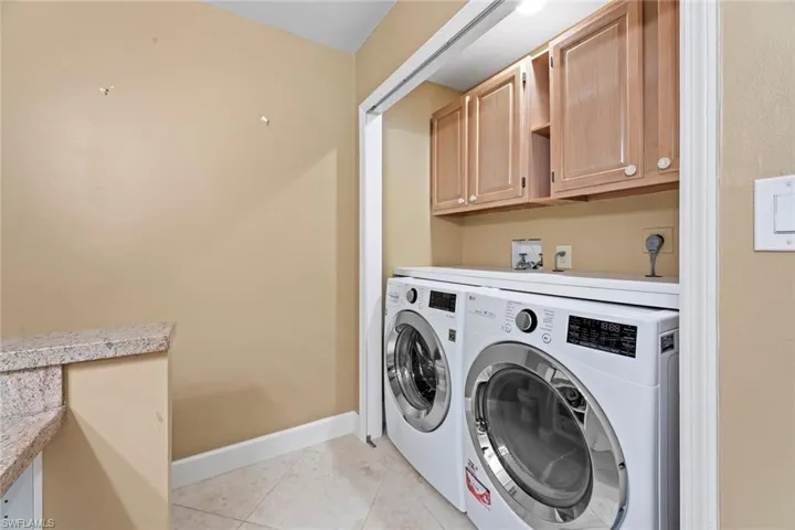 Laundry area with cabinets, hookup for a washing machine, electric dryer hookup, independent washer and dryer, and light tile floors