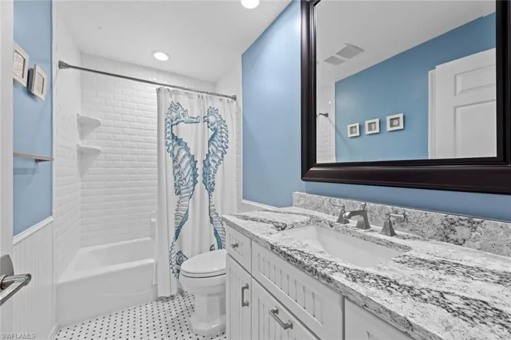 Full bathroom featuring tile floors, vanity with extensive cabinet space, toilet, and shower / bath combination with curtain