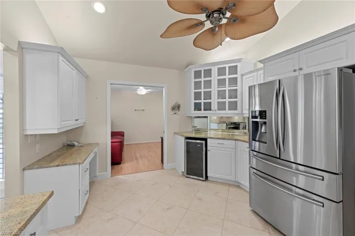 Kitchen featuring light tile flooring, beverage cooler, ceiling fan, white cabinetry, and stainless steel fridge