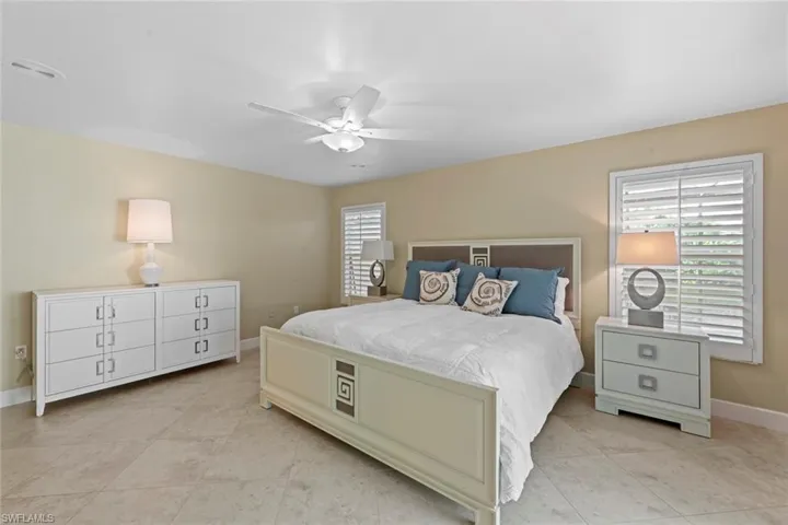 Bedroom featuring ceiling fan, light tile floors, and multiple windows