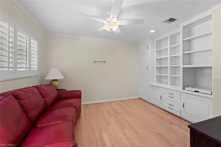 Living room with ceiling fan, light hardwood / wood-style floors, and ornamental molding