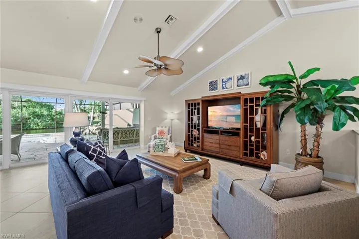 Living room with high vaulted ceiling, beamed ceiling, ceiling fan, and light tile floors