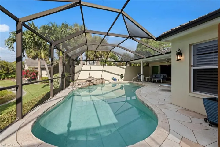 View of pool with a patio and glass enclosure