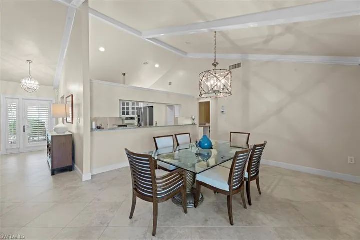 Dining room featuring high vaulted ceiling, beam ceiling, light tile floors, and a chandelier