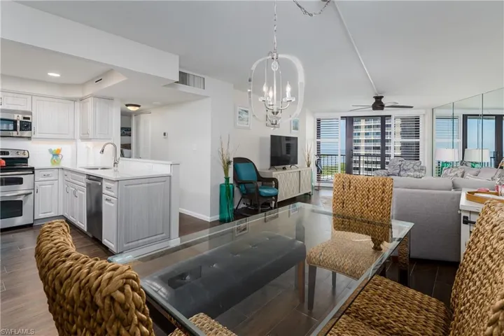 NEW open-concept kitchen and living area featuring tile flooring, white cabinetry, stainless steel appliances, and a glass-top dining table