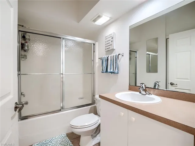 Bathroom with vanity, enclosed tub / shower combo, and light tile patterned floors