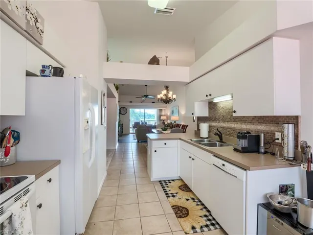 Kitchen featuring open floor plan, light tile patterned flooring, and white cabinetry