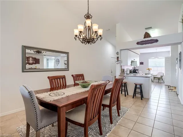 Dining area with a chandelier, light tile patterned floors, and high vaulted ceiling
