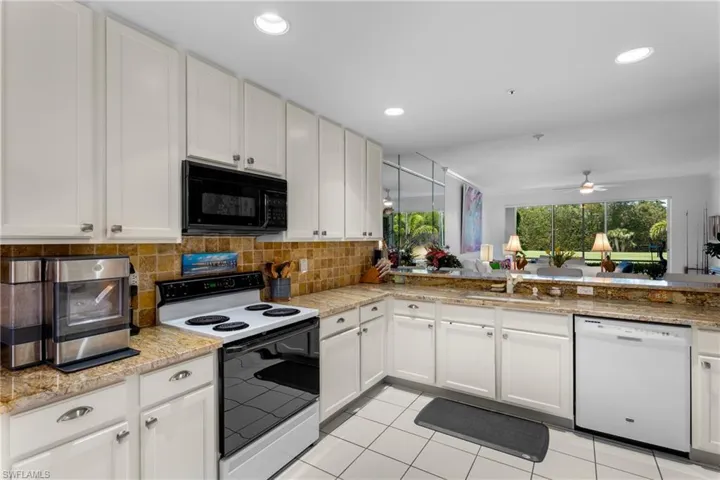 Kitchen featuring black microwave, backsplash, electric stove, dishwasher, and a sink