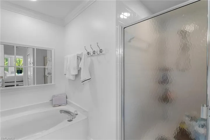 Full bath featuring ornamental molding, a garden tub, and a stall shower