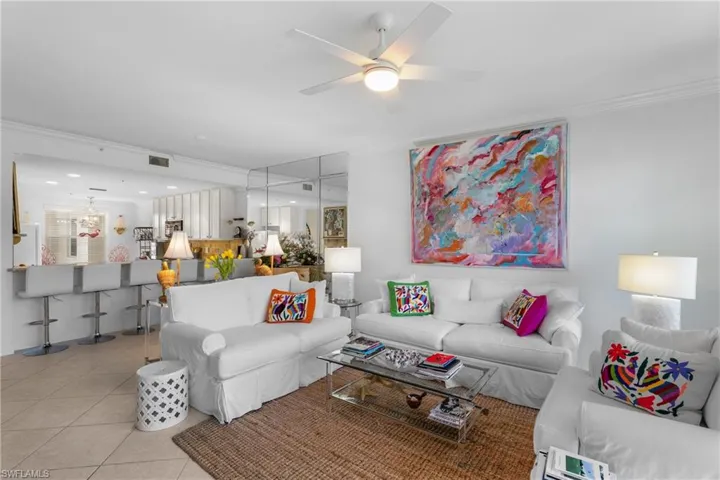 Living area with light tile patterned flooring, ceiling fan, ornamental molding, and visible vents