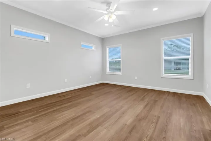 Master bedroom with ceiling fan, laminated flooring, and crown molding