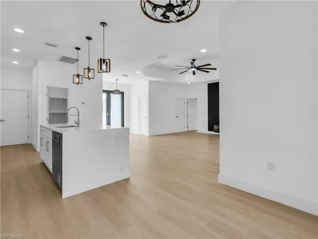 Kitchen featuring light stone counters, open floor plan, light wood-style floors, a ceiling fan, and white cabinetry