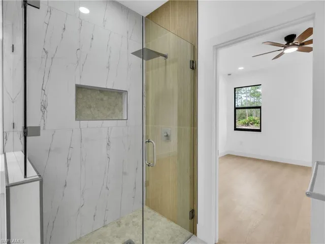 Full bath featuring a marble finish shower, a ceiling fan, recessed lighting, and wood finished floors