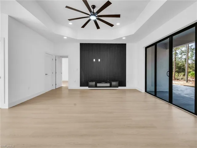 Unfurnished living room with a raised ceiling, a ceiling fan, light wood finished floors, and recessed lighting
