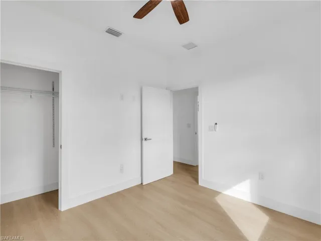 Unfurnished bedroom with light wood-style flooring, ceiling fan, and a closet