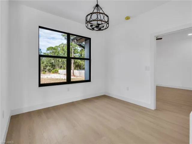 Spare room featuring light wood-type flooring and a chandelier