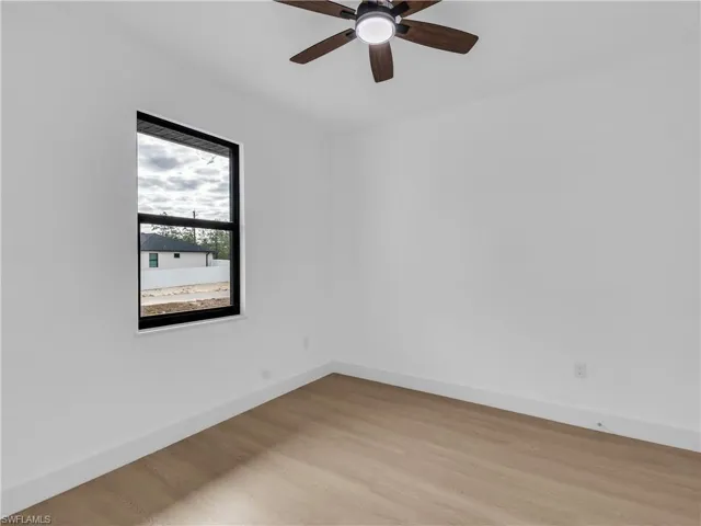 Empty room with wood finished floors and a ceiling fan