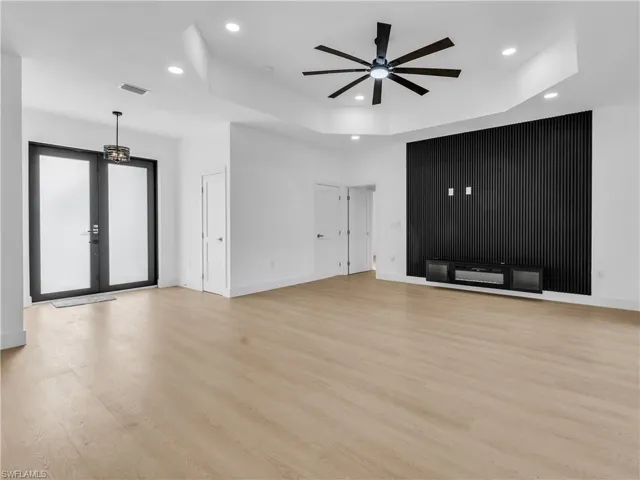 Unfurnished living room featuring a ceiling fan, light wood-style floors, recessed lighting, and a raised ceiling